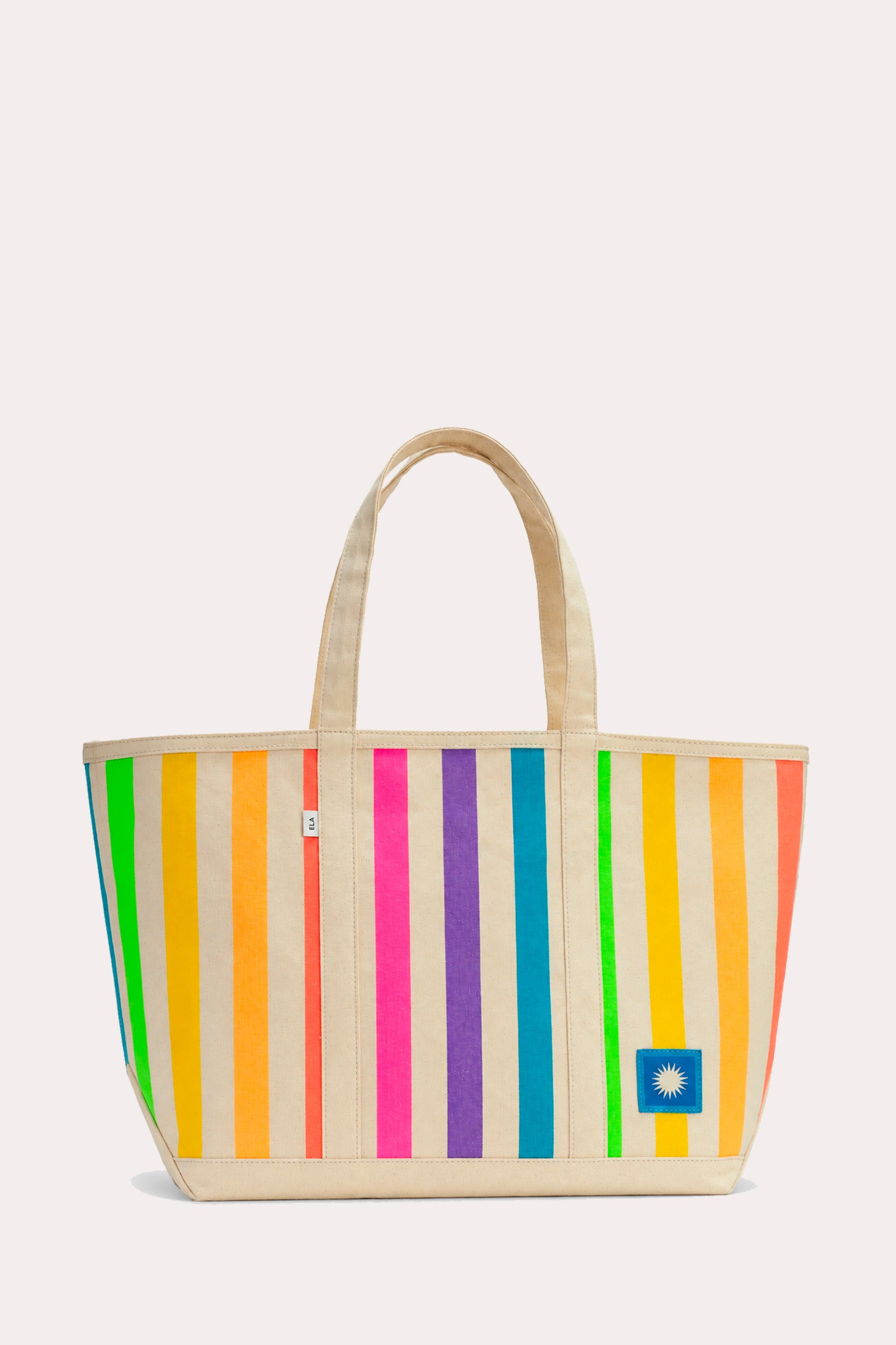 A canvas tote bag with vertical rainbow stripes in green, yellow, orange, pink, purple, blue, and white, featuring natural beige handles and a small blue square patch on the bottom right.